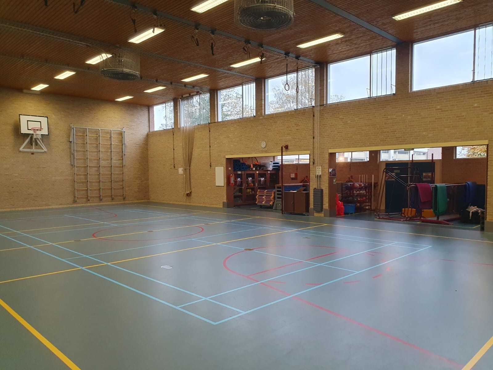 gymzaal met blauwe vloer en hoge ramen