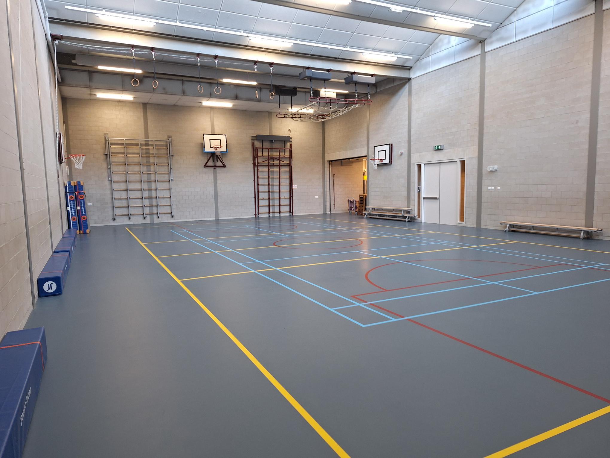 grijze gymzaal met blauwe vloer