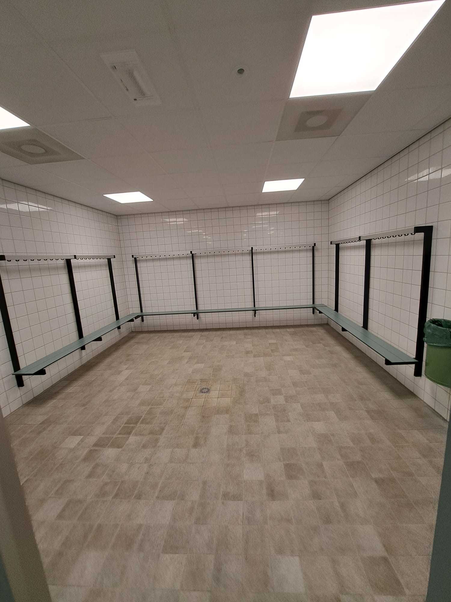 witte kleedkamer met tegelwanden en grijze vloer
