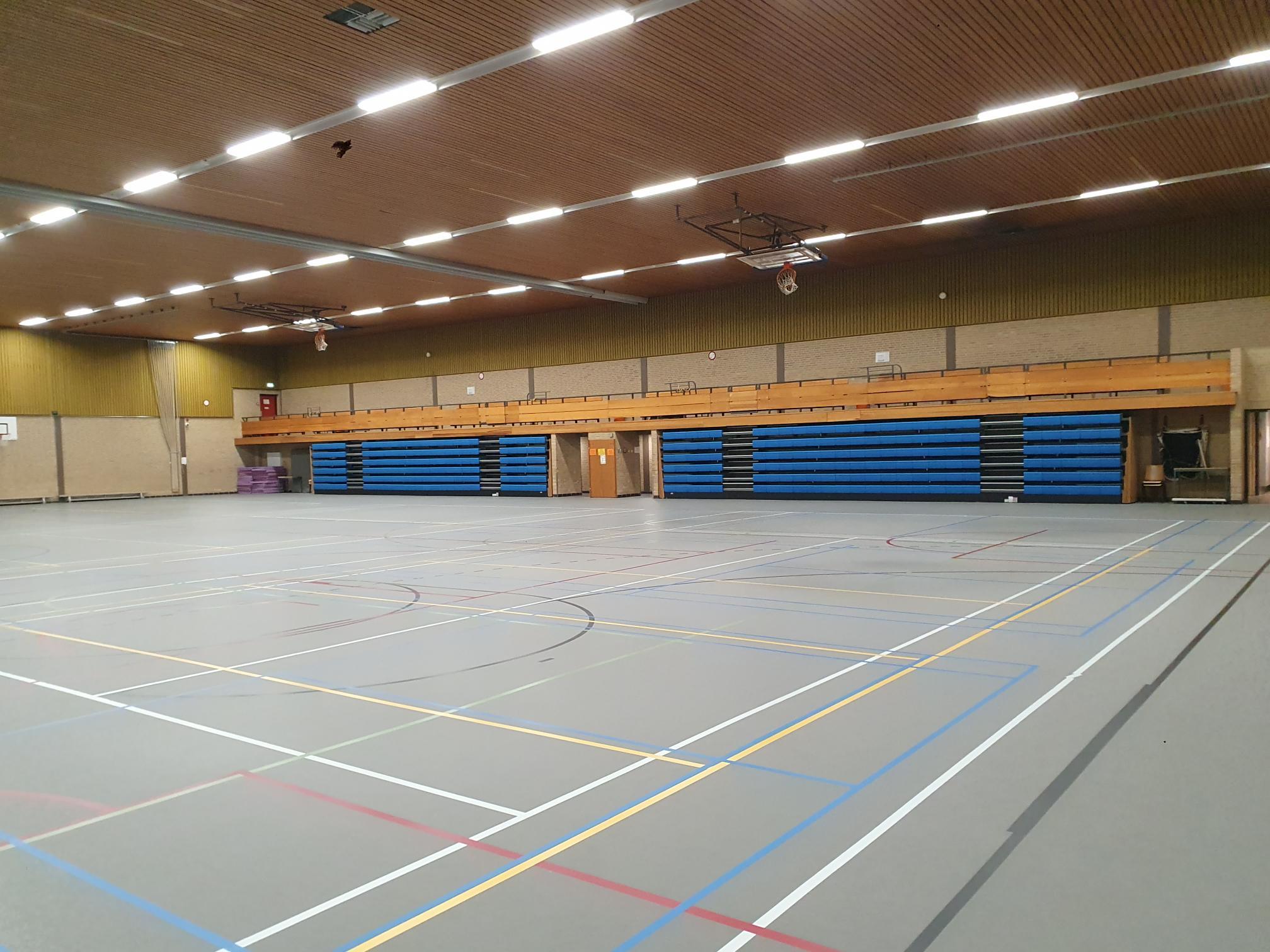 gymzaal met grijze vloer en houten plafond en tribunes