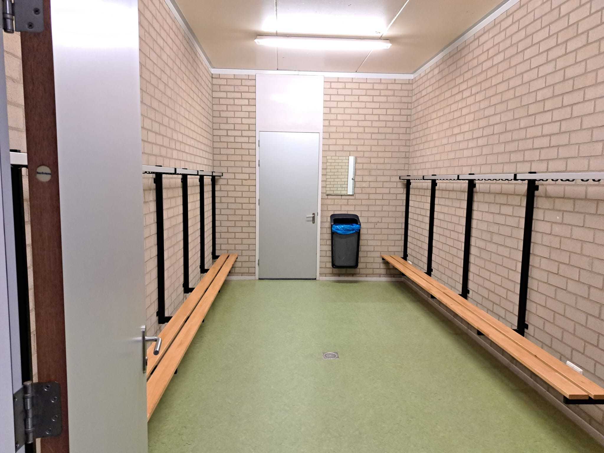 kleedruimte met grijze stenen muren en groene linoleumvloer
