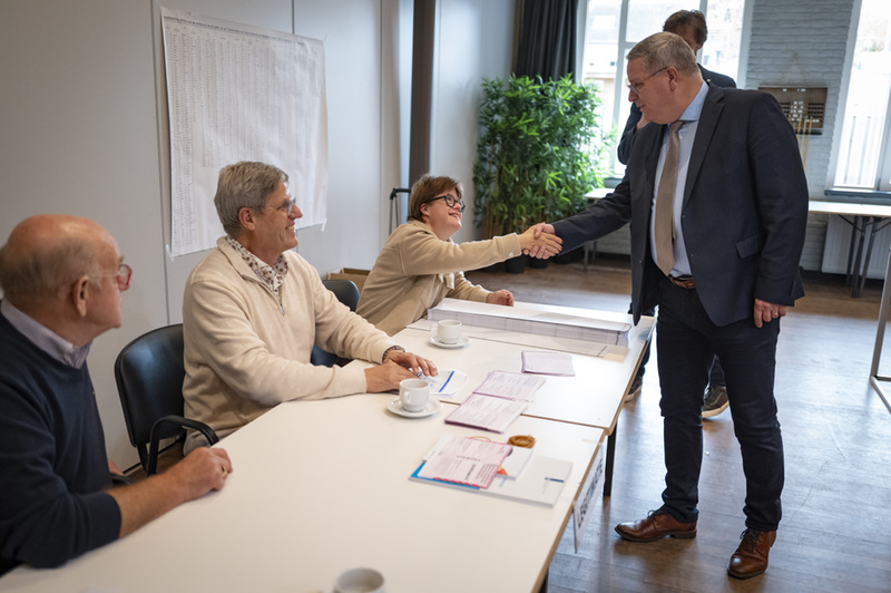 Burgemeester schudt prokkelmedewerker Mijke de hand in stemlokaal